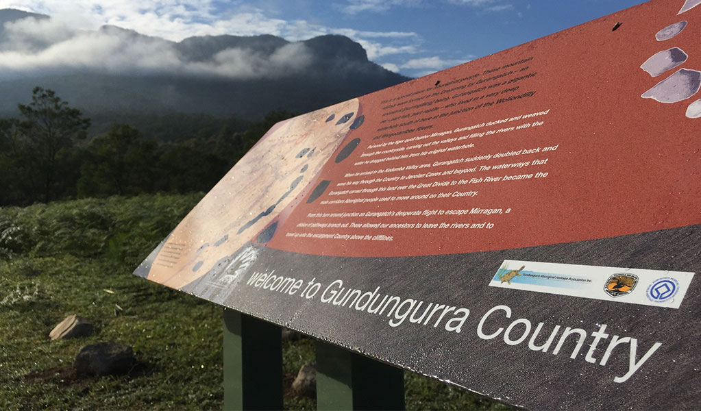An interpretive sign that welcomes visitors to Gungungurra Country with views of Blue Mountains National Park in the background. Credit: Yvonne Kaiser / DCCEEW &copy; DCCEEW