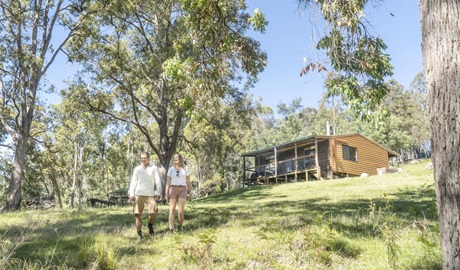 A couple walking down the hill outside Galong cabins in the Southern Blue Mountains area of Blue Mountains National Park. Photo: Simone Cottrell © DPIE