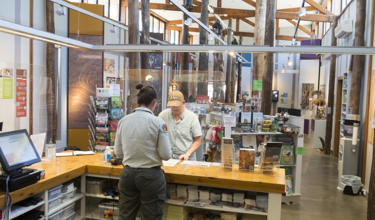 An NPWS worker gives advice to a visitor at the counter, Pilliga Forest Discovery Centre. Photo: Leah Pippos &copy; DPIE