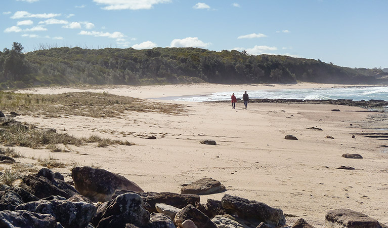 Couple walking on Monument Beach, Conjola National Park. Photo: Michael Jarman